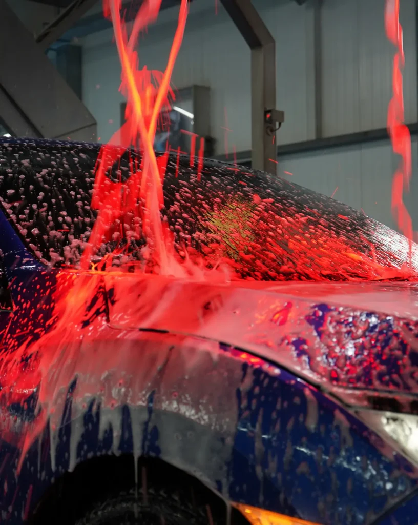 Een auto wordt behandeld met een rode schuimlaag in een carwash.